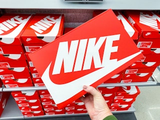 A person's hand taking a box of Nike shoes from a shelf.