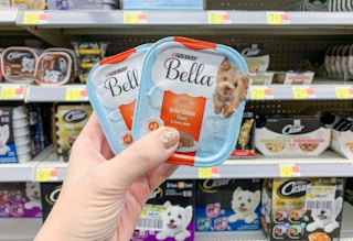 two trays of purina bella wet dog food trays held in front of shelves
