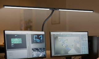 a desk lamp over two monitors