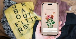 Someone holding a phone displaying the Anthropologie app next to an Urban Outfitters bag