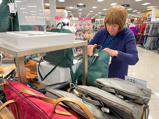 A woman looking at purses inside Kohls.