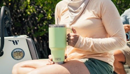 a person holding a lime green Yeti tumbler outside