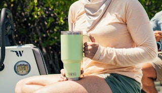 a person holding a lime green Yeti tumbler outside
