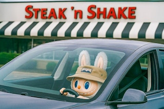 a large labubu in a car outside of steak n shake