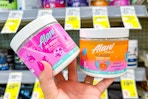 person holding 2 tubs of alani nu pre workout