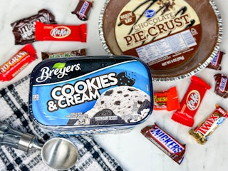 Breyers cookies and cream ice cream on a counter next to candy and pie crust 