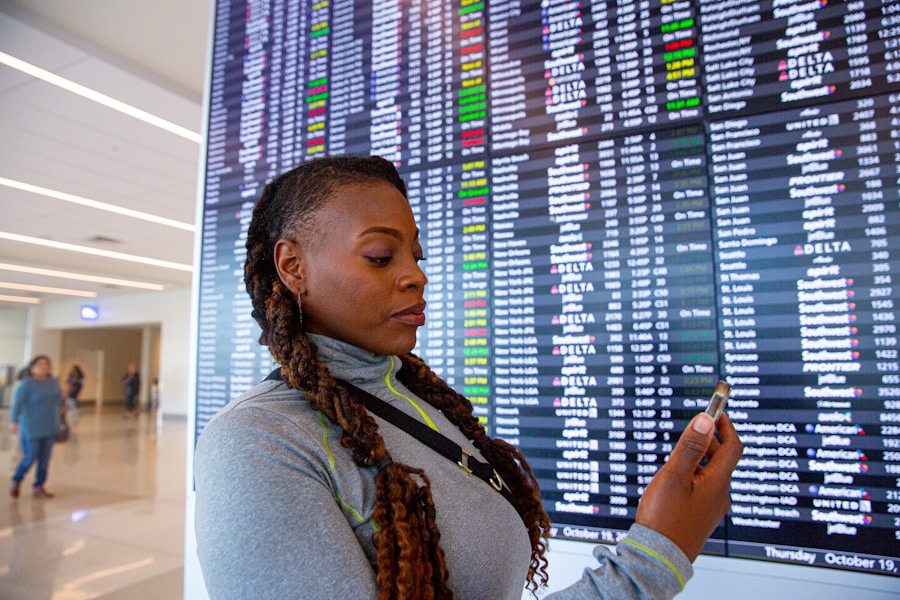 Person holding their phone in front of the Arrivals/Departures board