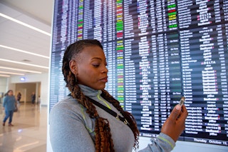 Person holding their phone in front of the Arrivals/Departures board