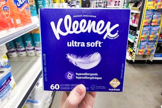 person holding a box of kleenex tissues in an aisle