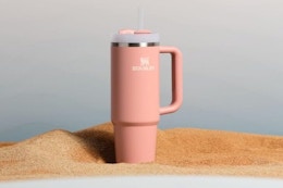 a stanley tumbler on sand