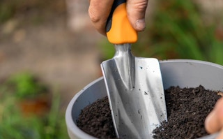 a trowel digging in a pot of soil 