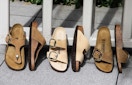 Three pairs of Birkenstock sandals displayed leaning up against a fence.