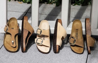 Three pairs of Birkenstock sandals displayed leaning up against a fence.