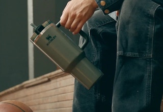 person holding a green stanley tumbler