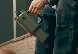 person holding a green stanley tumbler