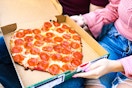 a couple sitting together looking at their heart shaped pizza