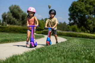 lifestyle image of children riding scooters on a sidewalk