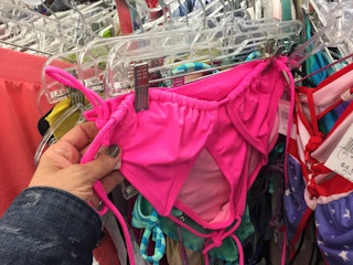 A person looking at a swimsuit on a rack at Goodwill