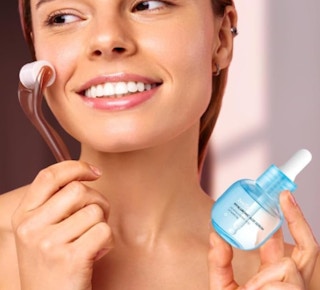 a woman holding a serum bottle and facial tool