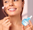 a woman holding a serum bottle and facial tool