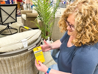 a woman holding a lowes clearance tag on a pation chair 