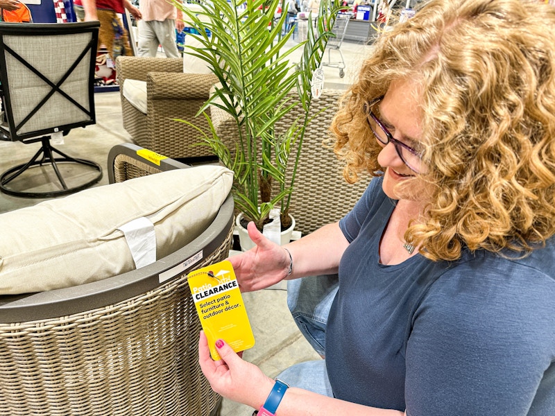 a woman holding a lowes clearance tag on a pation chair 