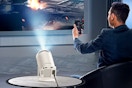 Lifestyle image of the Artsea Mini Projector being used by a man holding a remote
