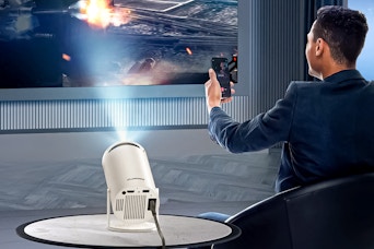 Lifestyle image of the Artsea Mini Projector being used by a man holding a remote