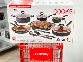 A 30-piece box set of Cooks nonstick essentials cookware sitting on a JCPenney shopping cart.