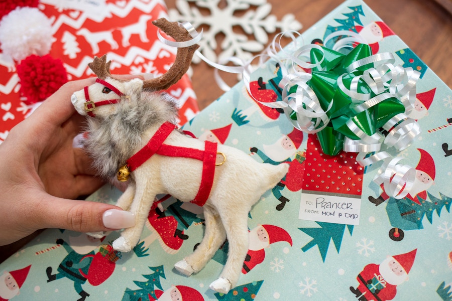 A gift with a tag that says Prancer next to a Christmas ornament