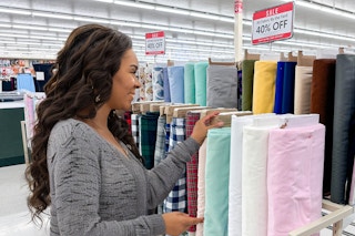 a woman in the hobby lobby fabric area looking at fabric on sale in store 