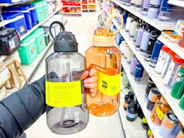 hand holding 2 all in motion water bottles in a target aisle
