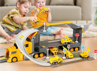 kids playing with a toy truck with a race track in a living room