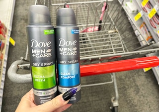 hand holding two dove men+care deodorant sprays in front of cart