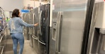 a person looking at fridges at best buy