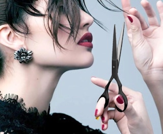 a person holding hair cutting scissors near their hair