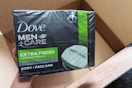 a hand holding a pack of bar soaps over a box