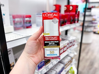 hand holding a L'Oreal Paris Bright Reveal UV Face Lotion at Target