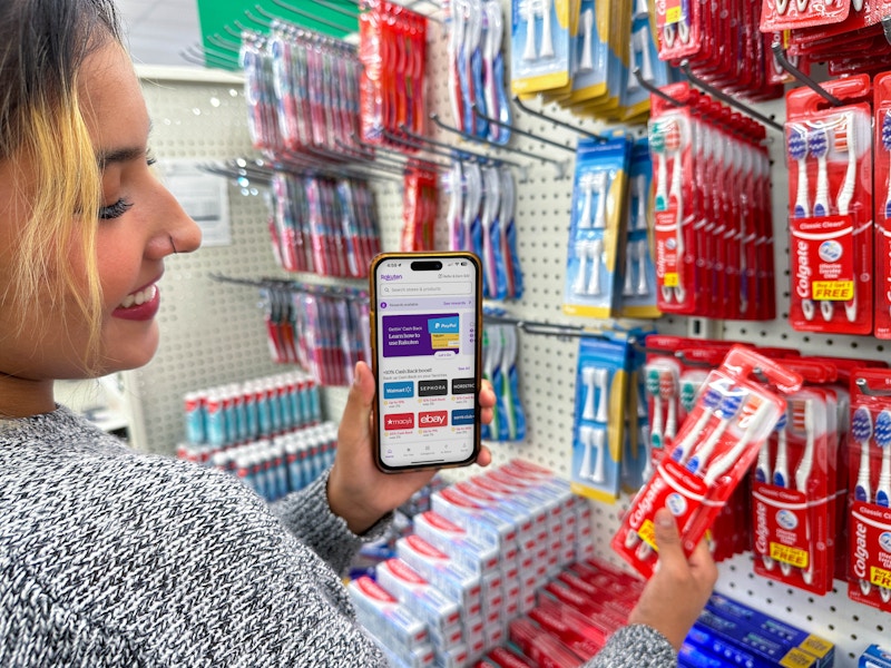 a person holding an iphone with a coupon app in the dollar tree store