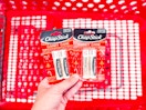 hand holding 2 chapstick holiday lip balm packs over a target cart