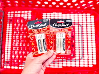 hand holding 2 chapstick holiday lip balm packs over a target cart