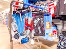 Three kids' swim trunks hanging on Walmart shopping cart: Transformers, Fortnite & Bluey