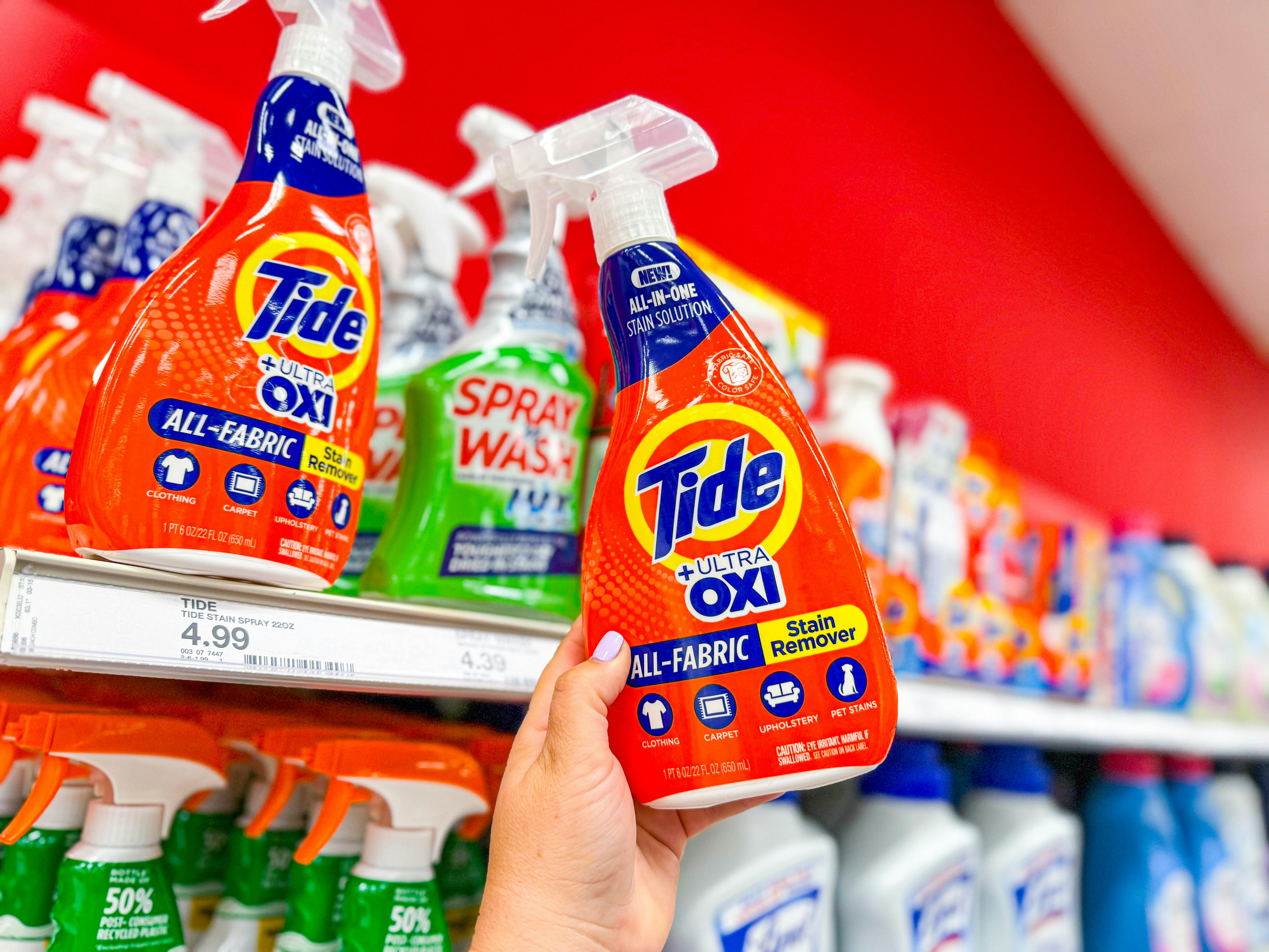 hand holding a bottle of tide laundry stain remover in front a target shelf