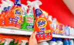 hand holding a bottle of tide laundry stain remover in front a target shelf