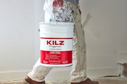 A 5-gallon paint bucket of Kilz Original Primer being carried into a room for DIY work