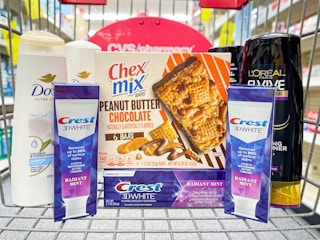 a cvs shopping cart filled with grocery items, l'oreal and dove shampoo and conditioner, chex mix cereal bars, crest toothpaste