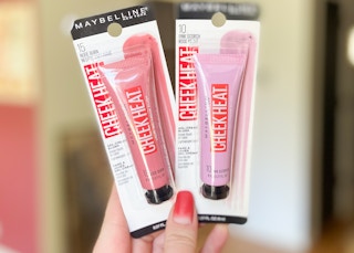 hand holding two maybelline cheek heat cream blush makeup