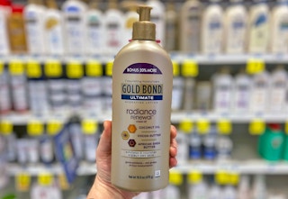 a hand holding a gold bottle of lotion