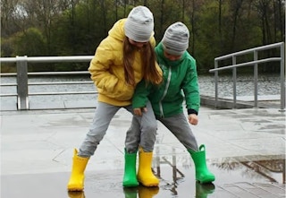 two kids wearing Crocs rain boots outside