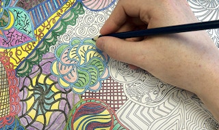 hand colors in an adult coloring book